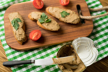 Liver pate on the bread on wooden tray.