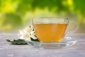 Jasmine tea with jasmine flowers on a grey stone table.