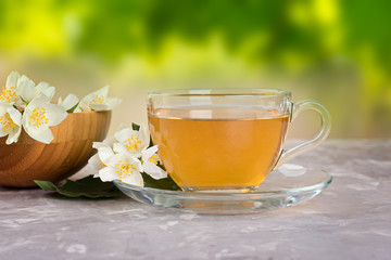 Jasmine tea with jasmine flowers on a grey stone table.