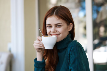 Woman sitting in cafe, young woman drinking from mug