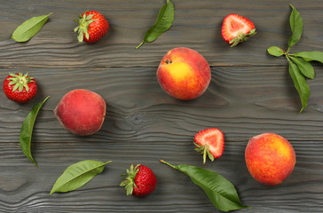 peach fruit with strawberry and green leaf on dark wooden background. top view with copy space