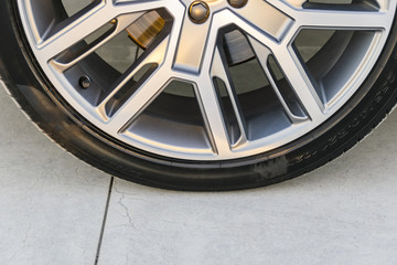 Tire and alloy wheel of a modern car on the ground, car exterior details