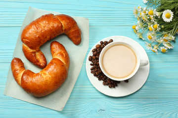 Coffee background. Cup of coffee with croissant and coffee beans on blue wooden background. Top view with copy space.