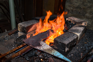 Warming up the metal in heat. The forge.