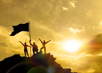 Foto op Plexiglas Silhouettes of three people holding a victory flag on top of a mountain, family. A man on top of a mountain. Concept idea, success in business. Against the sky at sunset. © gerasimov174
