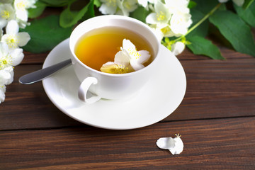 Tea with jasmine in a white cup on a wooden table.