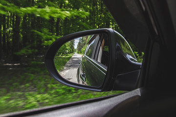 A view in the side view mirror. Mirror rear car. Reflection of the road