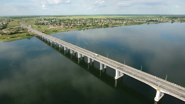Amazing view on  a modern car bridge in Kherson region crossing the Dnipro river and shot from a bird`s eye perspective in a sunny day in summer. The riverscape and cloudscape look gorgeous.