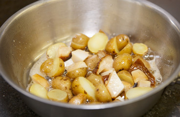 Baby potatos and mushrooms being fried in pan