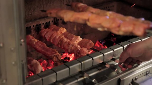A person sets skewers with meat on a brazier with burning coals. The cook cooks a meat dish of pork on fire. The person starts to lay beef in a barbecue. Before filling portions, the food was prepared