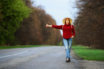 Beautiful smiling woman standing on road catches car, auto stop, autimatic braking gear, traveler