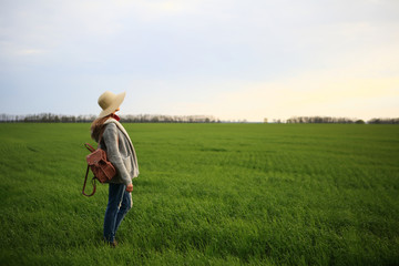 Girl in hat,with backpack, standing in grass green field, space, sky, nature, natural background