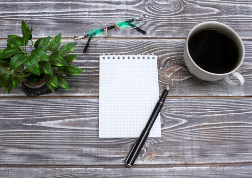 Blank notepad and pen with cup of coffee on office wood table background. Business concept with copy space for any desing