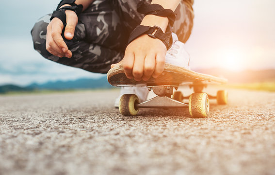 Boy Sits On The Skateboard Legs And Hands Closeup Image