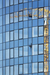 Reflection of construction crane on the glass of tall multistoried office building