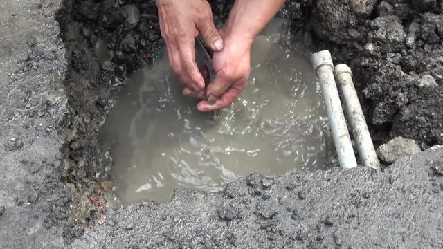 Hands of a worker that is repairing a pipe in a water leak on a road in Taipei, capital of Taiwan.