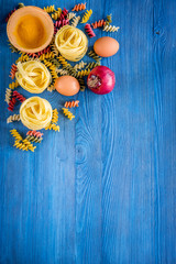 Food ingredients for Italian pasta on blue wooden desk background top view copyspace