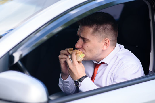 Man Eats A Burger In The Car.