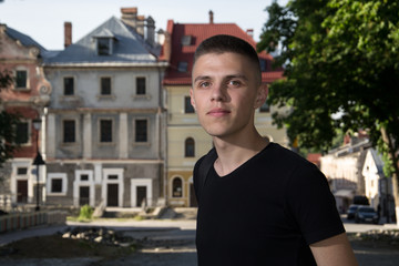 happiness and people concept - smiling man in black t-shirt over house background