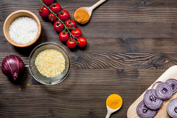 paella home cooking with rice, tomato, onion and spices for ingredients on wooden background top view space for text