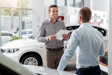 Outgoing client speaking with agent in automobile showroom