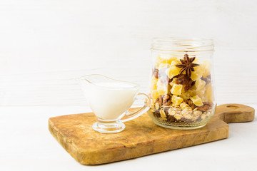 Healthy breakfast in jar with dried fruits, and milk on white wooden background