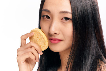 Woman with sponge, woman rubs her face with sponge on isolated background portrait