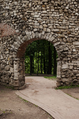 Vertical location of an arch and a stone wall, paths and forests in the background