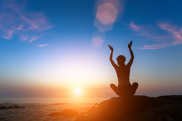 Yoga silhouette. Woman on the ocean during amazing sunset.