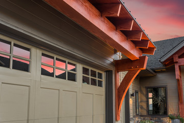 Beautiful Luxury Home Exterior Detail at Sunset: Garage Door with Partial View of Front Entrance and Colorful Sunset Sky