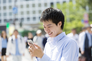 渋谷スクランブル交差点でスマホを見て笑みをこぼす男性