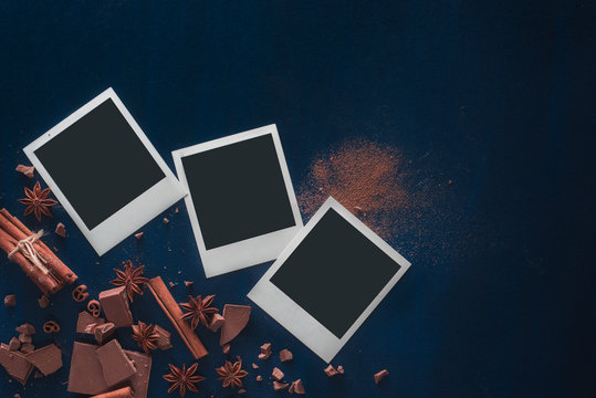 Printed instant photos with cocoa powder, chocolate and cinnamon on a black background