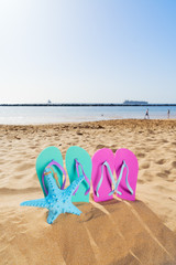 Summer beach fun - summer colorful blue and pink sandals with starfish in beach sand