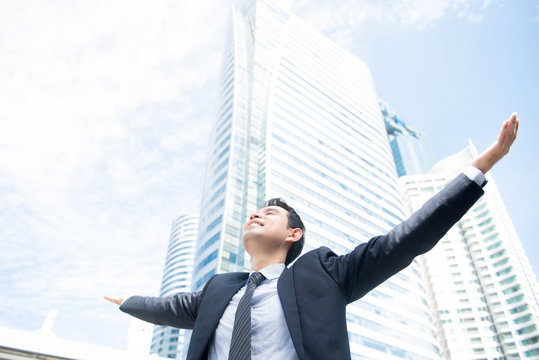 Businessman raising his arms, open palms, with face looking up to the sky