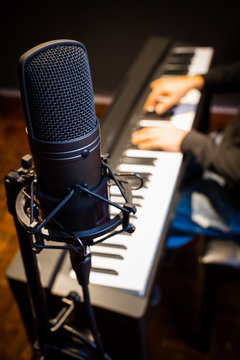 condenser microphone on musician hands playing piano background