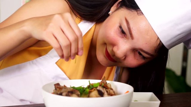 Portrait of a female chef garnishing a bowl of Indonesian food oxtail soup in the restaurant