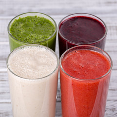 Fresh avocado, strawberry, blueberry and banana drinks on wooden table, assorted protein cocktails with fresh fruits.