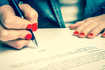Female hand signing contract to conclude a deal