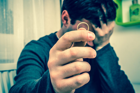 Man is holding wedding ring - divorce concept