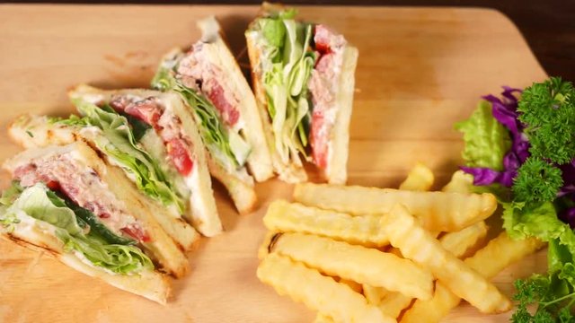 Video footage of top view of tasty sandwich sliced on a wooden cutting board with french fries, shot in the restaurant