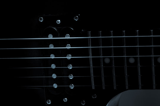 Part of the electric guitar on black background. A place for writing of the text.