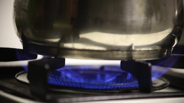 A pot is placed on the gas burner. Gas flame. There are bright blue flames due to gas.