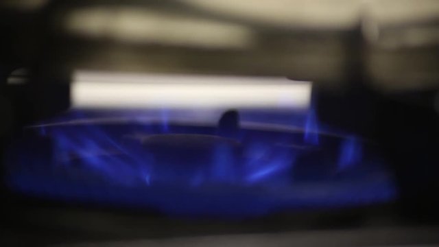 A pot is placed on the gas burner. Gas flame. There are bright blue flames due to gas.