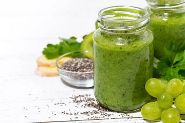 healthy green fruit and vegetable smoothies in jars on white background