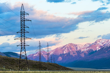 Obraz premium High voltage transmission towers with mountains on background 