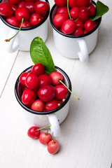 Cherry in enamel cup on white wooden background. Healthy, summer fruit. Cherries...