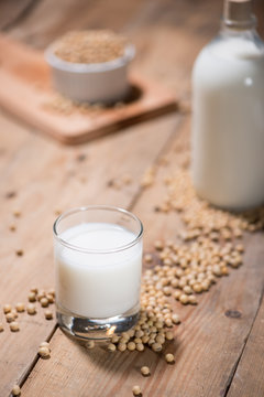Soy milk or soya milk and soy beans in spoon on wooden table.