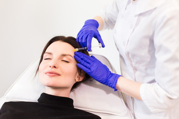 A woman on the procedure of injections in a cosmetology clinic