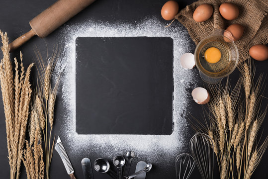 Baking ingredients: egg and flour on black board.