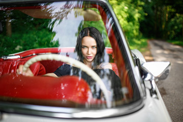 Beautiful girl in a black hat driving vintage car